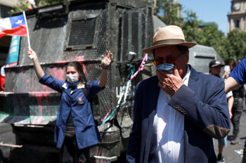 متظاهر يحاول تغطية وجهه من أثار قنابل الغاز