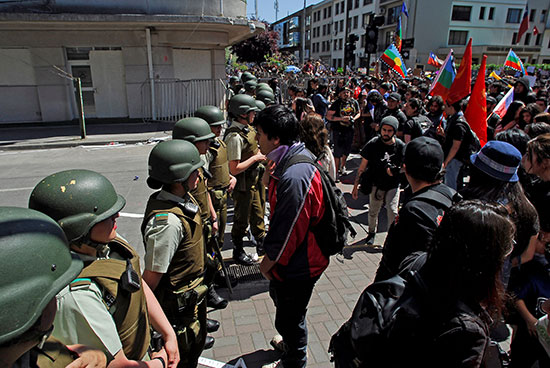 متظاهرون يقفون أمام ضباط الشرطة الشيلية خلال المظاهرة