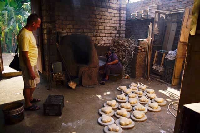 عضو بفريق الأوركسترا الأوكرانية يشهد طهى الخبز البلدى فى الفرن بالاقصر