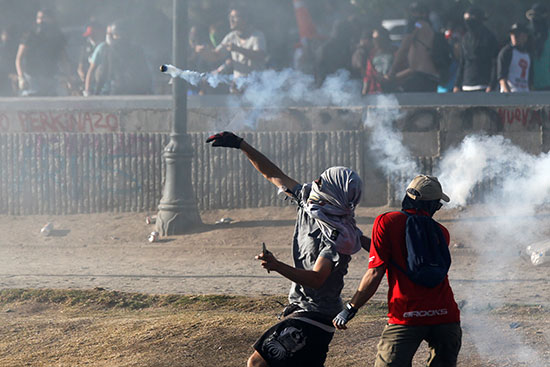 متظاهر يرد بقنبلة غاز على قوات الأمن