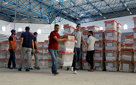 يحمل موظفو الاقتراع صناديق الاقتراع والمواد الانتخابية لتوزيعها على مراكز الاقتراع في تونس