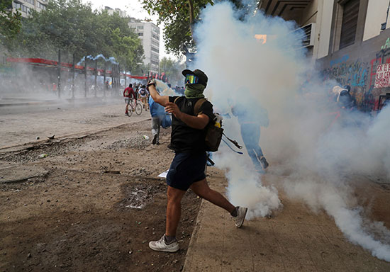 متظاهر يرد قنبلة الغاز على أفراد الشرطة