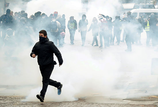 متظاهر يركض بعيدا عن دخان الغاز