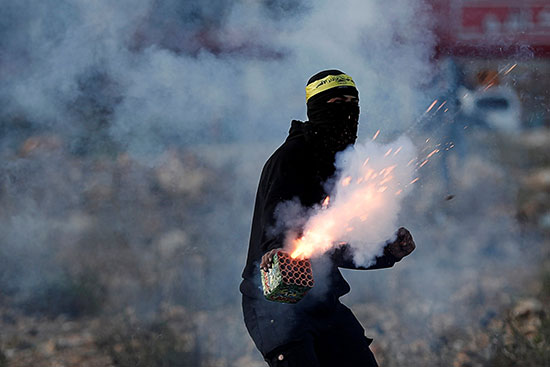 متظاهر فلسطيني يطلق ألعاب نارية أثناء مظاهرة مناهضة لإسرائيل بالقرب من مستوطنة بيت إيل