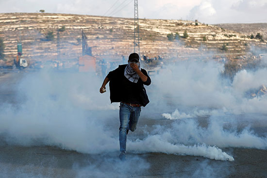 متظاهر فلسطيني يهرب من الغاز المسيل للدموع الذي أطلقته القوات الإسرائيلية