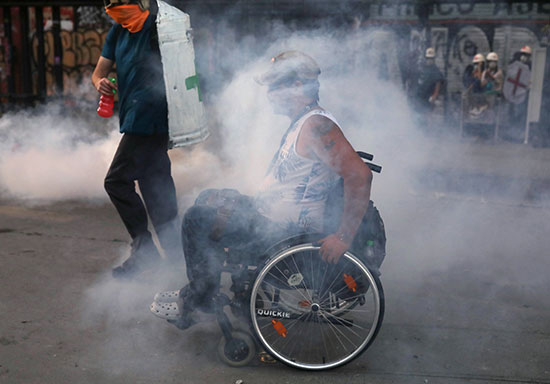 متظاهر على كرسى متحرك وسط أدخنة الغاز