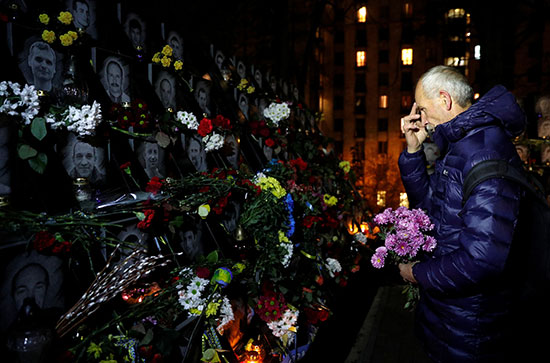 أوكرانى يضع الزهور على النصب التذكارى للضحايا