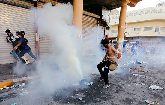 يحاول متظاهر عراقي إطفاء الغاز المسيل للدموع خلال الاحتجاجات المستمرة المناهضة للحكومة