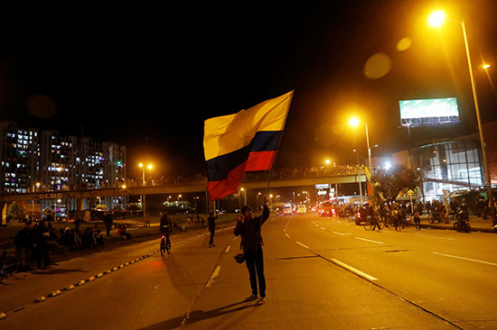متظاهر-يرفع-العلم-الكولومبيى-اثناء-احتجاجات-عارمة