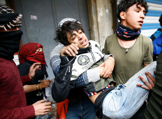شباب-يحملون-مصابا-من-جراء-الغاز-المسيل-للدموع-في-احتجاجات-العراق