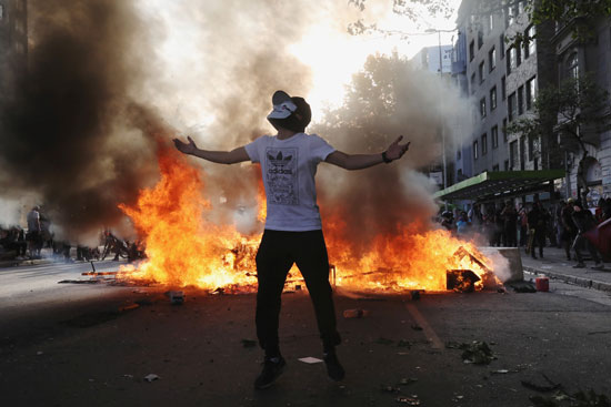 متظاهر يخلد لحظات الفوضى بصورة أمام النيران