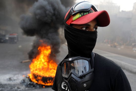 متظاهر-عراقى-و-خلفه-كاوتش-محترق-ببغداد