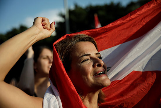 متظاهرة تحمل العلم اللبناني تصرخ بشعارات في مسيرة نسوية خلال الاحتجاجات المستمرة المناهضة للحكومة في بيروت