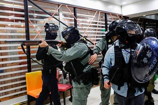 شرطة مكافحة الشغب تحمل بندقية أثناء تفريق المتظاهرين المناهضين للحكومة في مركز تجاري في تاي بو بهونج كونج