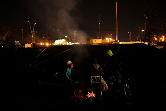 طالبو اللجوء المكسيكيون يسخنون أنفسهم بالقرب من نار خارج خيامهم حيث انخفضت درجات الحرارة