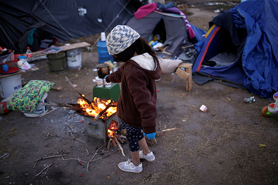 طالبة لجوء مكسيكية تدفئ نفسها أمام شعلة نار