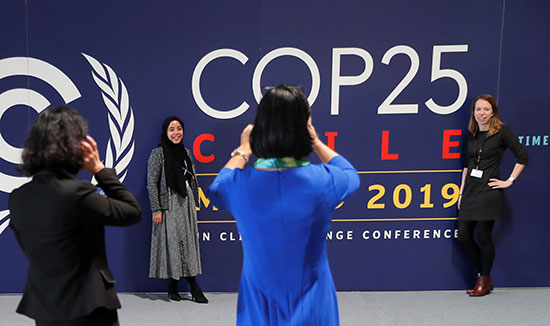أشخاص يلتقطون صورة تحمل شعار مؤتمر الأمم المتحدة المعني بتغير المناخ