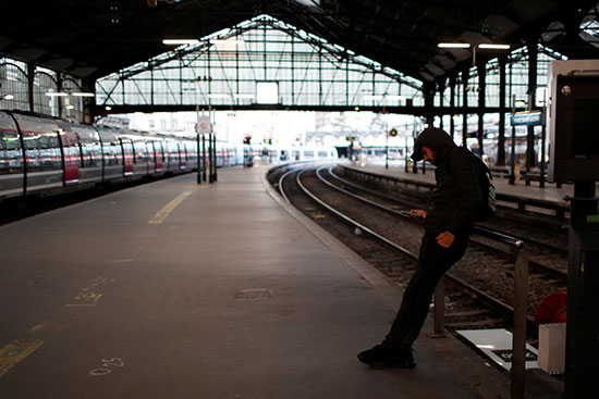 يستخدم مسافر هاتفه المحمول أثناء انتظاره على منصة في محطة سان لازار للسكك الحديدية