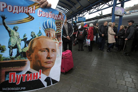 مواطنون يرفعون صور الرئيس الروسى فلاديمير بوتين احتفاء بالقطار الجديد