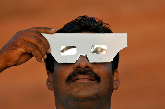 رجل يشاهد كسوف الشمس فى الهند