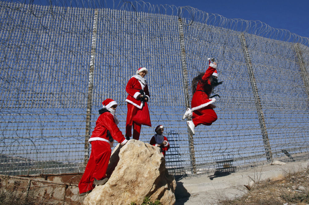 فلسطينيون يرتدون زى بابا نويل عند حاجز بالقرب من مدينة بيت لحم بالضفة الغربية