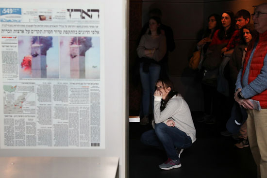 فتاة تنظر إلى الأعداد التذكارية للصحف الأمريكية ويبدو عليها الحسرة