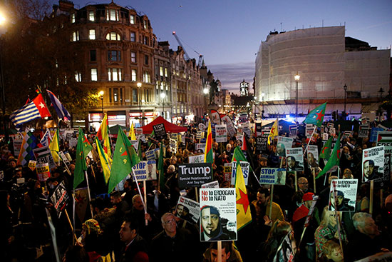 المتظاهرون يحملون لافتات وأعلام أثناء فى مظاهرة أثناء حضور ترامب قمة الناتو