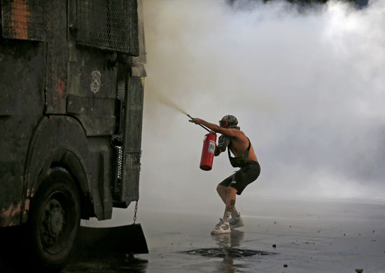 متظاهر يستخدم طفاية حريق ضد مركبة مصفحة أثناء احتجاج