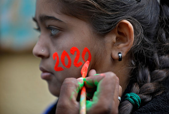 فتاة ترسم وجهها فى أرقام عام 2020 خلال الاحتفالات فى الهند