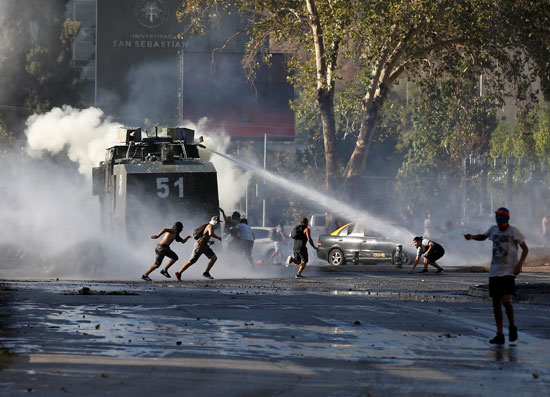 المتظاهرون يركضون من مدفع مياه أثناء احتجاج ضد حكومة تشيلي
