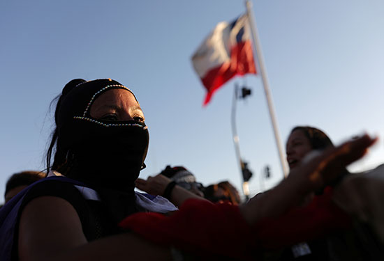 امرأة ترتدي قناعًا تشارك في احتجاج معارض للعنف ضد المرأة