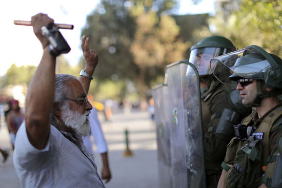 مواطن تشيلى يقف أمام قوات الأمن
