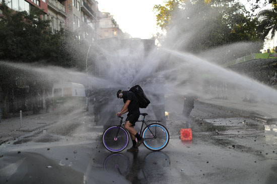 متظاهر يقود دراجته محاصر برشاشات المياه التى أطلقتها الشرطة