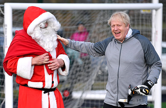 جونسون يحيي رجلاً يرتدي زي بابا نويل أثناء عملية الاحماء قبل مباراة كرة القدم البناتية