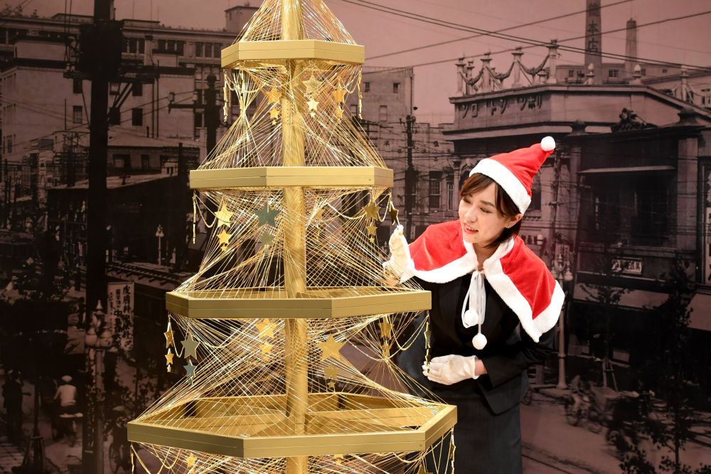 موظفة في بيت المجوهرات الياباني جينزا تاناكا Ginza Tanaka  تعرض شجرة عيد الميلاد الذهبية التي تقدر بثمن 1.8 مليون دولار في طوكيو، 2016