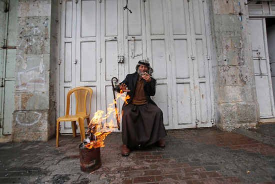 رجل-فلسطيني-يجلس-بالقرب-من-متجر-مغلق