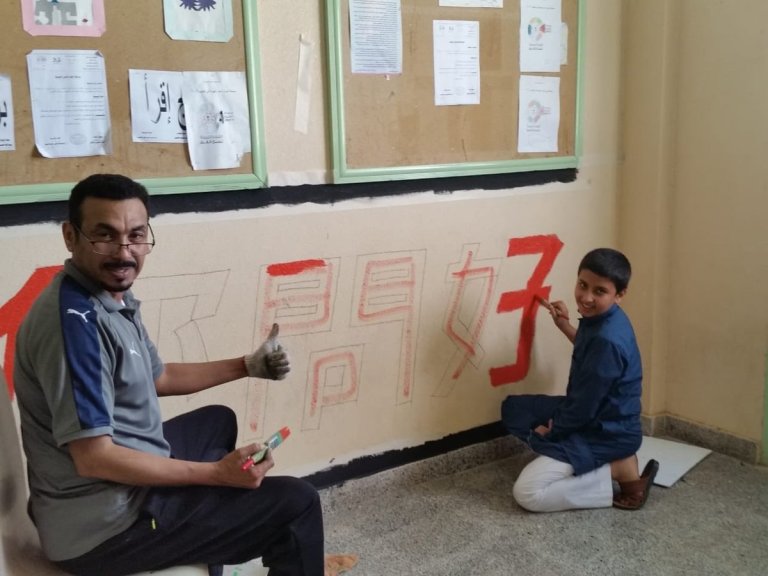 كتابة عبارة صينية على حائط مدرسة سعودية