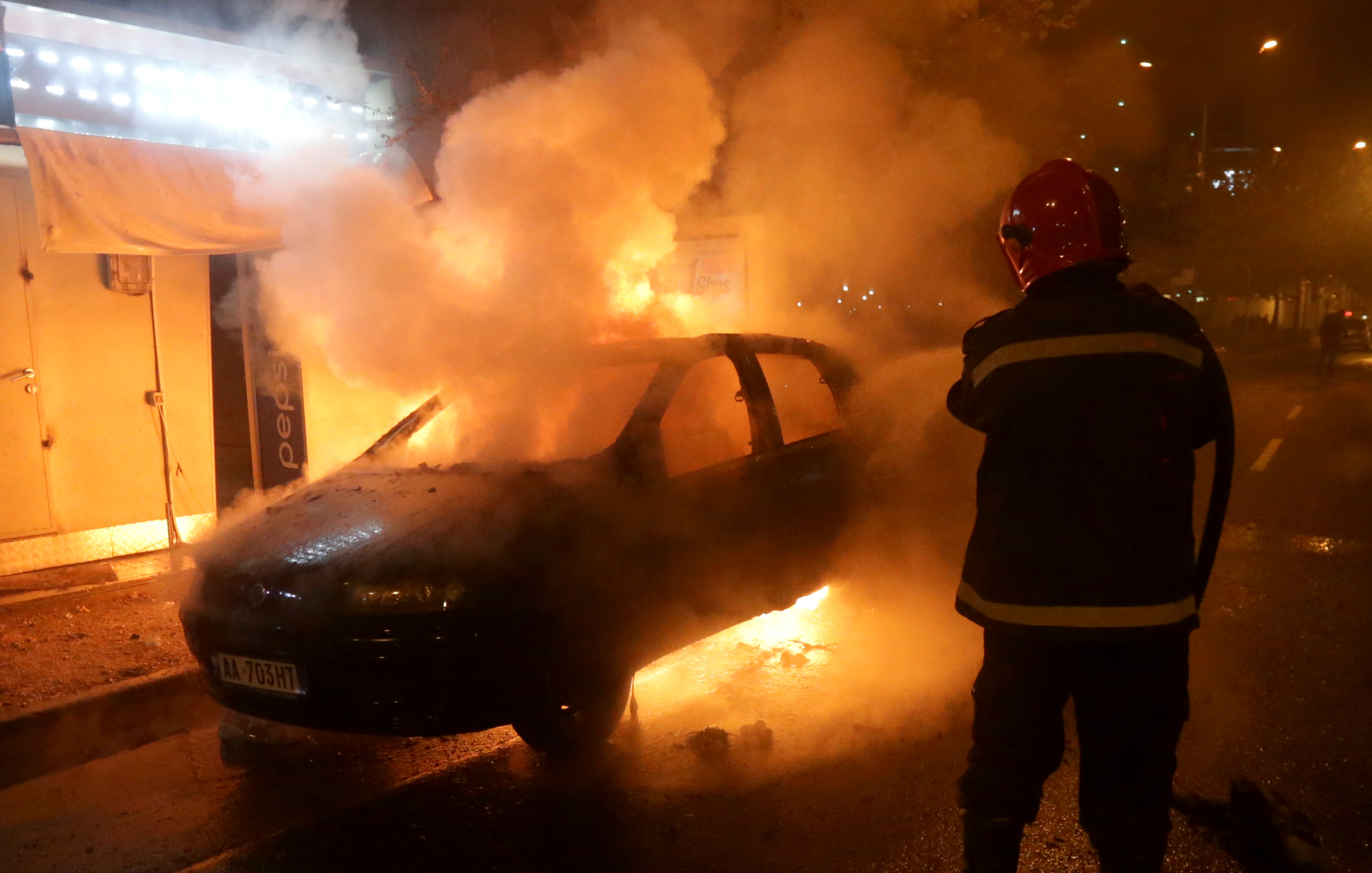 رجل إطفاء يطفئ سيارة مشتعلة خلال مظاهرة مناهضة للحكومة بالقرب من مبنى البرلمان في تيرانا