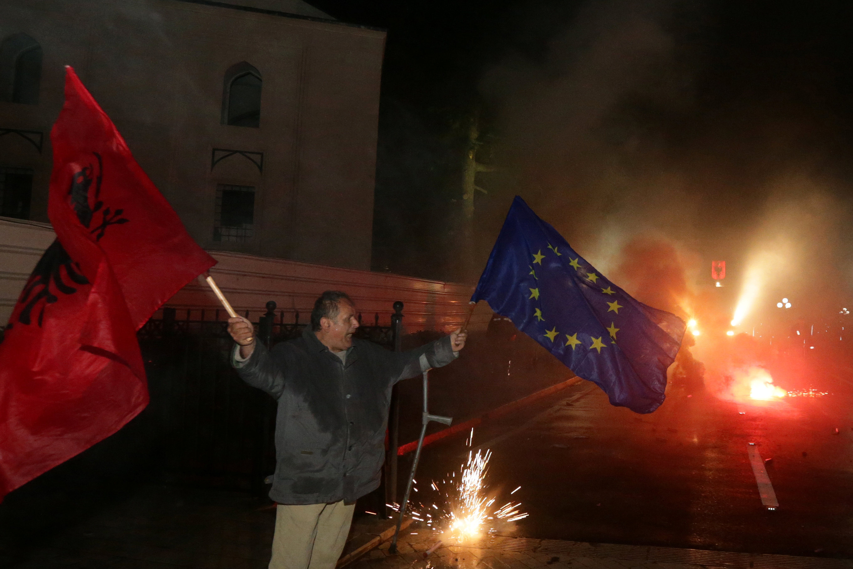 أحد أنصار حزب المعارضة يلوح بالعلم الألباني والأوروبي خلال مظاهرة مناهضة للحكومة أمام مبنى البرلمان في تيرانا