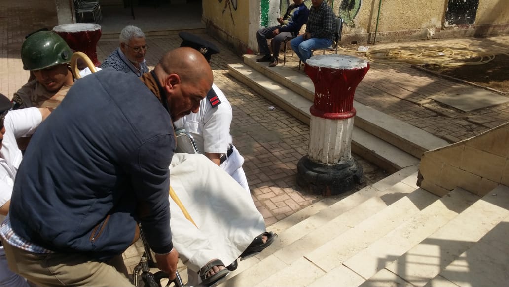أفراد الشرطة يحملون مسن يجلس على كرسى متحرك للإدلاء بصوته (2)