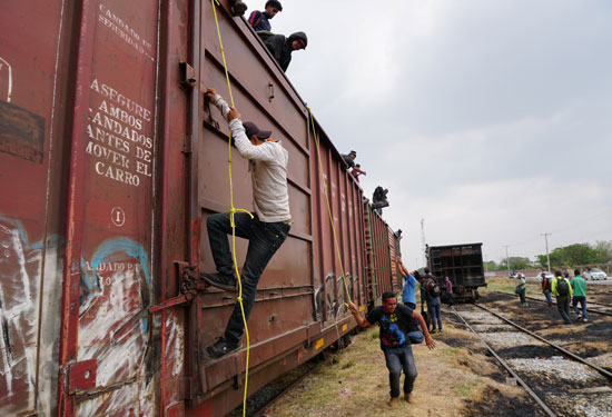 جحافل-المهاجرين-يتسلقون-قطار-تجارى-(7)