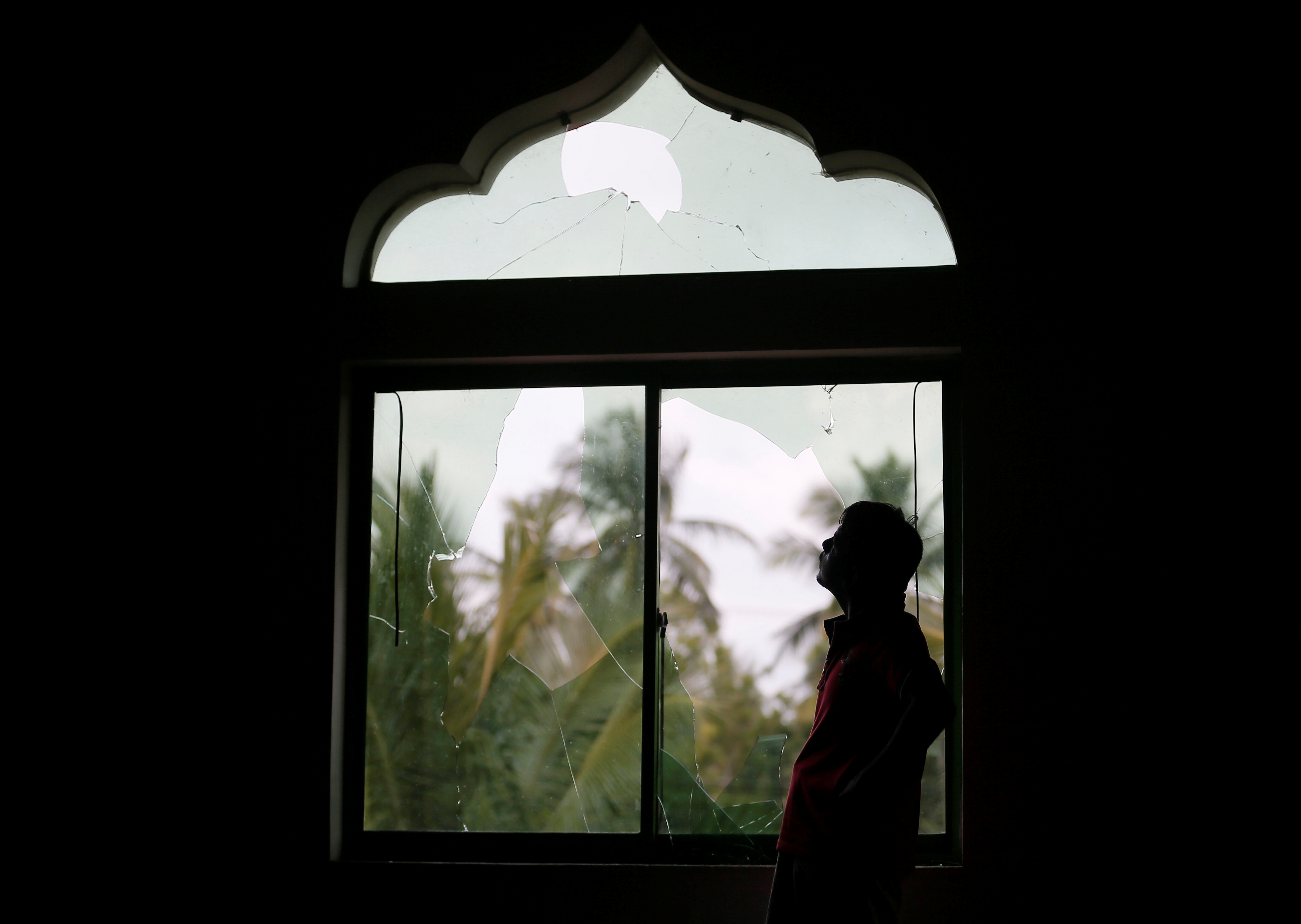 مواطن سريلانكى يقف أمام نافذة المسجد الذى هاجمه الغوغاء