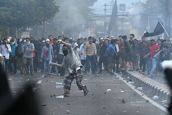 متظاهر يلقى الحجارة على الشرطة الإندونيسية