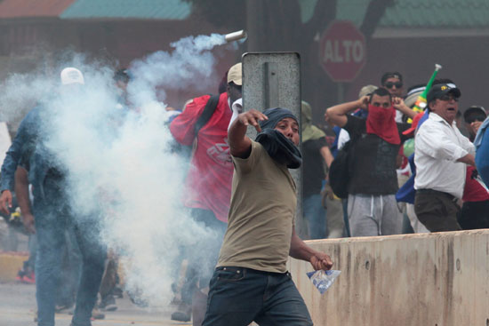 أحد المتظاهرين يطلق الغاز المسيل للدموع