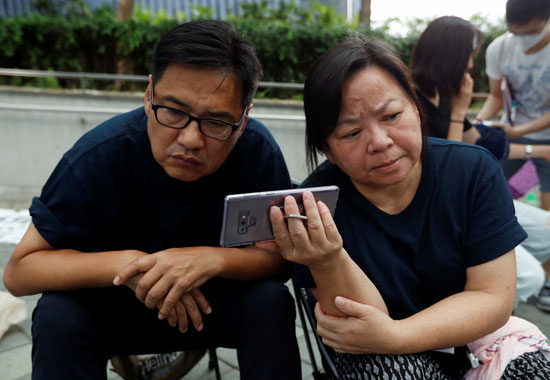 رجل وزوجته يتابعان خطاب كاري لام الرئيسة التنفيذية لهونج كونج عبر الهاتف