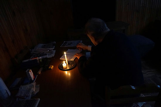 مواطن يباشر عمله على ضوء الشموع