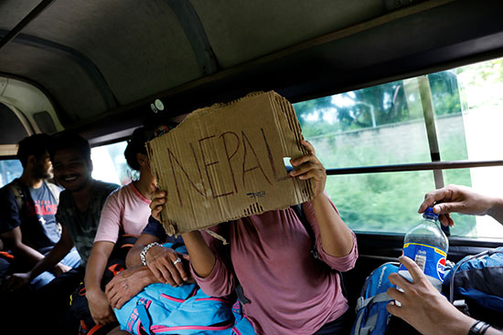 مهاجرة تحمل لافتة مكتوب عليها اسم دولتها نيبال