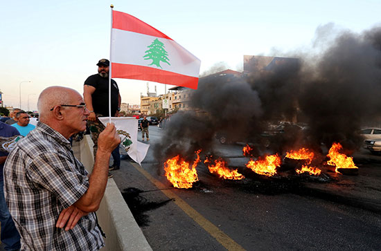 متظاهر يرفع علم لبنان