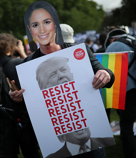 متظاهر يرتدى قناع بصورة ميجان ماركل