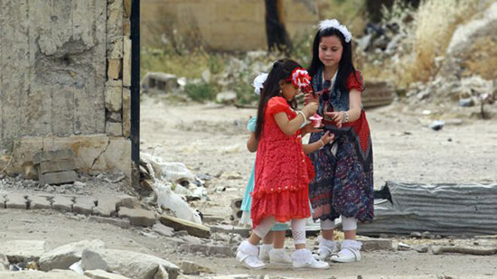 طفلتان بملابس العيد الجديدة تتناولان المثلجات في مدينة الرقة السورية